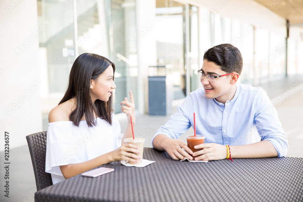 Teenage Couple Talking While Having Drinks In Shopping Mall Teenage Couple Talking While Having Drinks In Shopping Mall