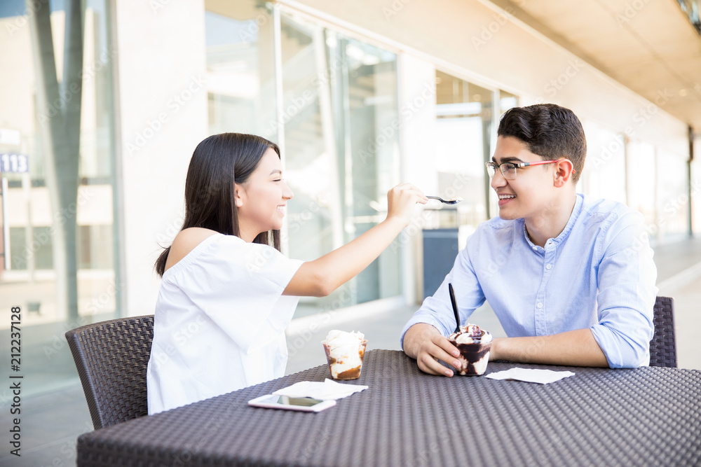 Girl Feeding Icecream To Boyfriend In Cafe Girl Feeding Icecream To Boyfriend In Cafe