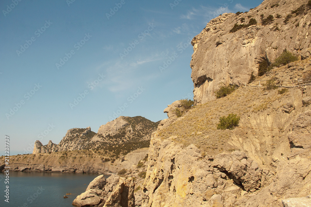 Mountain landscape, rocks and reefs surrounding the blue Bay of the Black sea. Crimea.