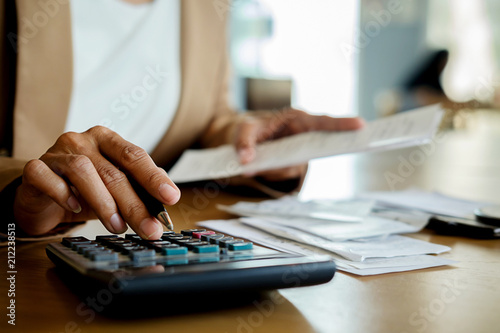 Woman with bills and calculator. Woman using calculator to calculate bills at the table in office. Calculation of costs.