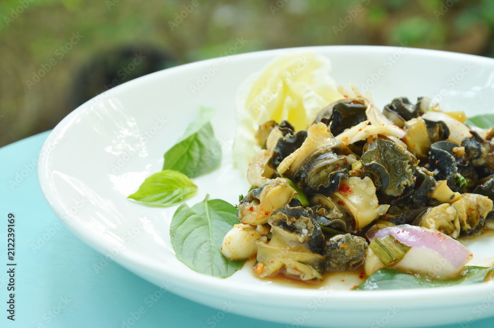 spicy golden apple snail with herb salad on white plate spicy golden apple snail with herb salad on white plate