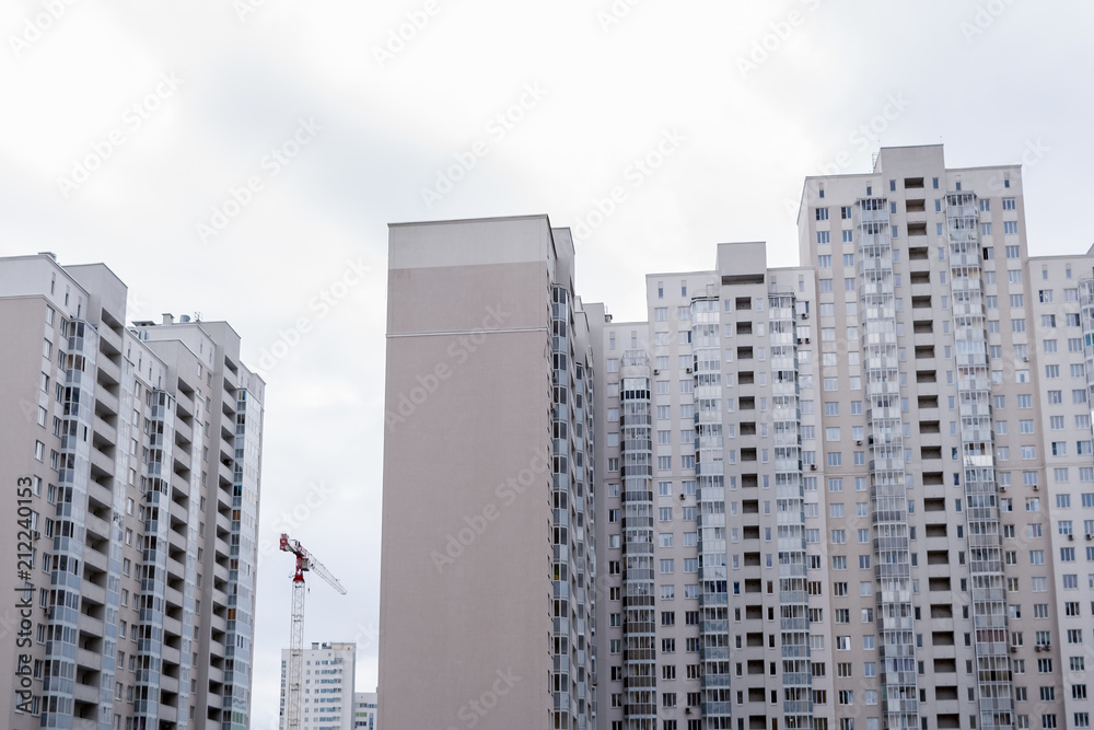 Naklejka premium New grey multi-storey residential buildings and construction crane.