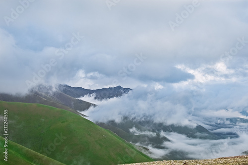 mountain valley and mountain peaks with the remains of snow on the slopes closed by low dense clouds landscape illustration background