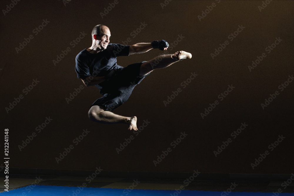 Kicking in a jump in the performance of an athlete in black gloves