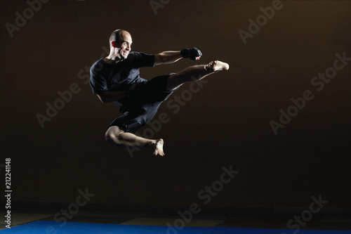 Kicking in a jump in the performance of an athlete in black gloves © andreyfire