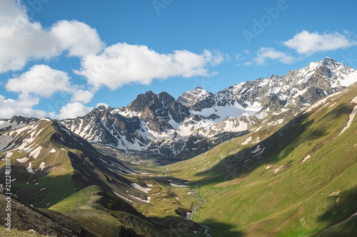 mountain valley overgrown with green grass with the remains of snow on the slopes of the mountain peaks landscape illustration background