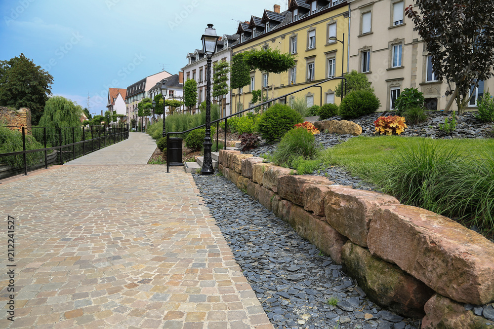 Moderner Garten und Landschaftsbau: Mauer aus Natursteinen und Weg aus Natur Pflastersteinen an der Promenade entlang des Flusses Lauch in Colmar, Elsass Moderner Garten und Landschaftsbau: Mauer aus Natursteinen und Weg aus Natur Pflastersteinen an der Promenade entlang des Flusses Lauch in Colmar, Elsass