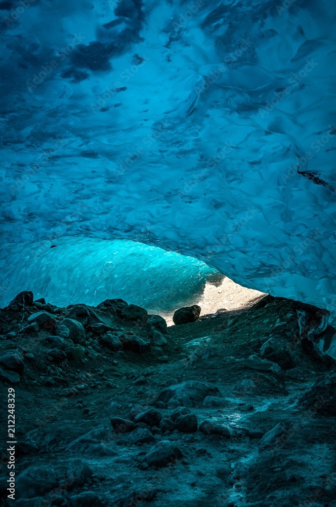 Entrance to an ice cave under the Perito Moreno Glacier, El Calafate, Patagonia, Argentina. Sunlight penetrates through the glacier and cast a hue of blue and turquoise on textured ice surface.