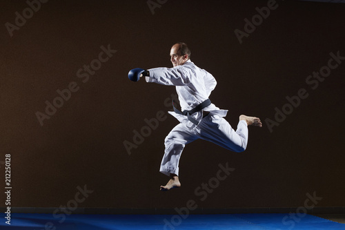In karategi, an adult athlete trains punch hand in jump
