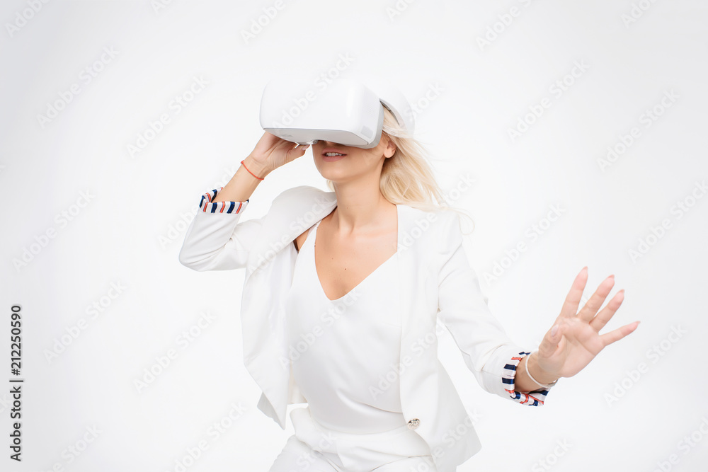 Blond woman in white suite with virtual reality goggles. Studio shot on white background Blond woman in white suite with virtual reality goggles. Studio shot on white background