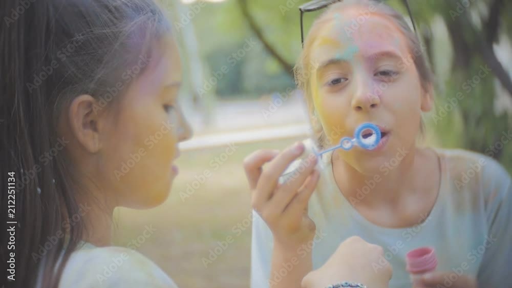 Two girls soiled dry colors Holi laugh and blow bubbles Two girls soiled dry colors Holi laugh and blow bubbles