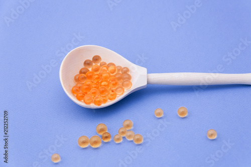 A wooden spoon with red caviar on a blue background.