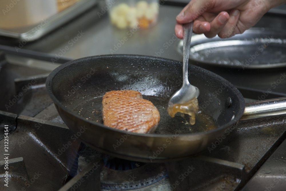 The cook fry the duck fillet in a frying pan. Gas hob The cook fry the duck fillet in a frying pan. Gas hob