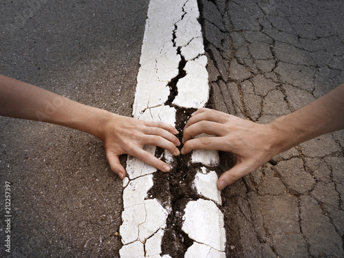 фотографія Fighting couple hands pull apart land and white line on asphalt road arguments r