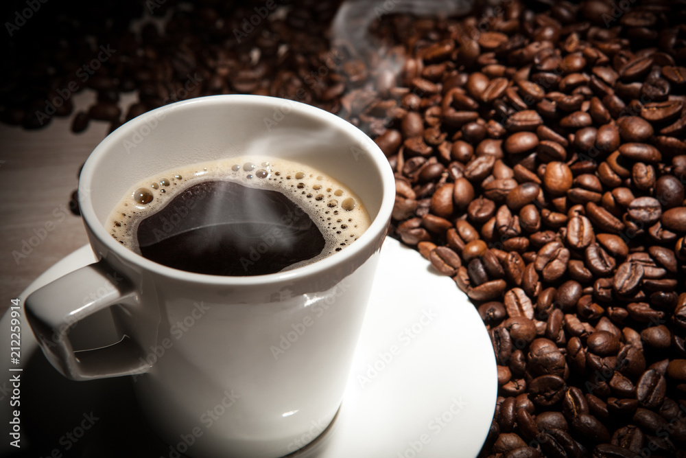 white cup of coffee with steam against a background of fried coffee beans white cup of coffee with steam against a background of fried coffee beans