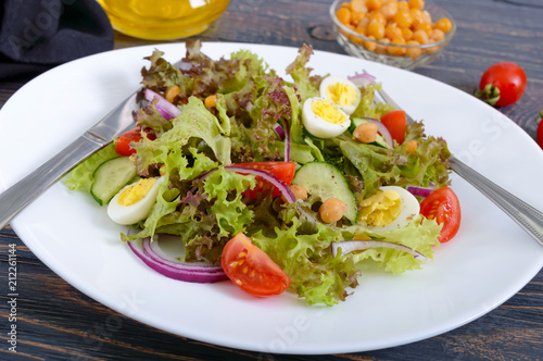 Light summer salad with fresh vegetables, greens, quail eggs and chickpeas. Vegetarian dish. Proper nutrition. Close-up.