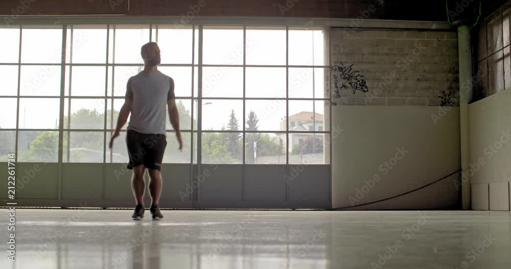 Young adult man doing jumping jacks exercise during fitness sport workout.Front view .Grunge industrial urban training.4k slow motion video