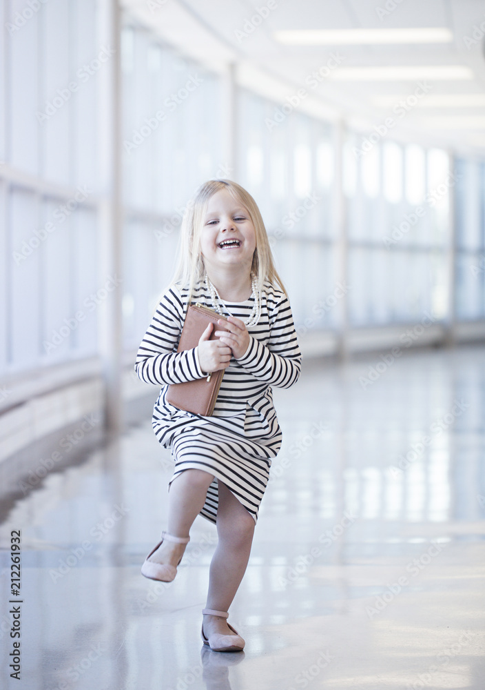 Portrait of laughing little girl wearing striped dress dancing