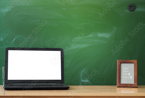 Teacher, student desk table. Education background. Education concept. Laptop with blank screen and photo frame on the table with blackboard background.