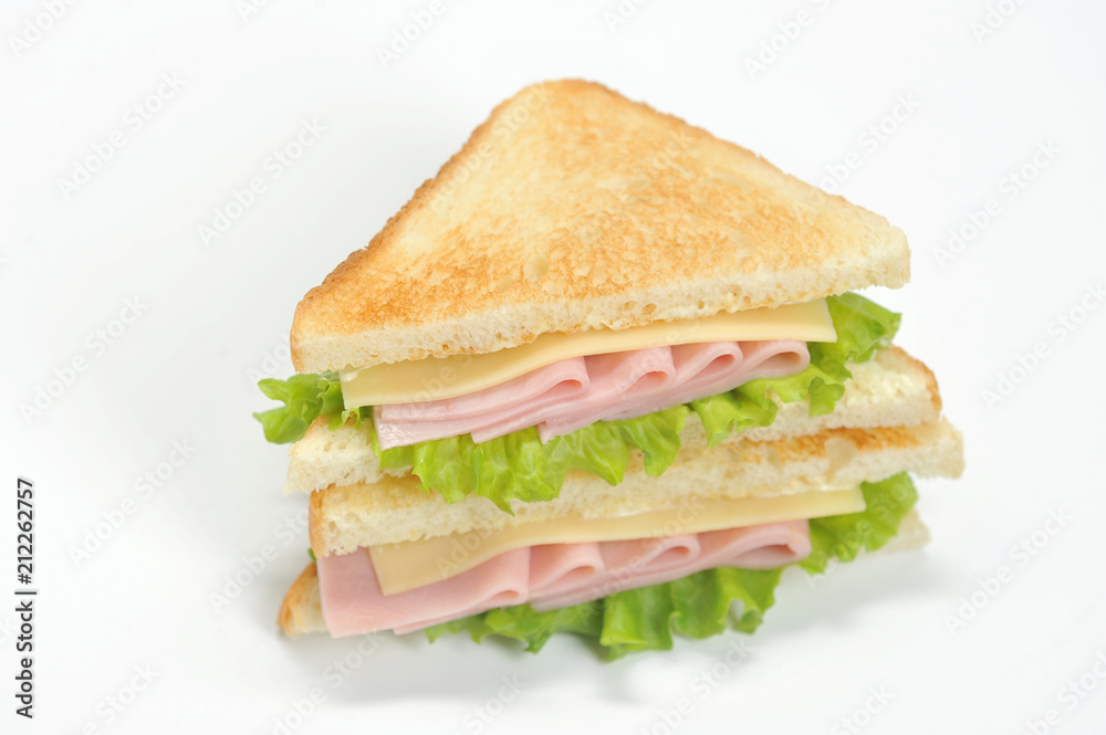 A classic sandwich with ham, cheese and lettuce leaves. Slices of white bread are roasted. White background. Close-up. Macro photography. A classic sandwich with ham, cheese and lettuce leaves. Slices of white bread are roasted. White background. Close-up. Macro photography.