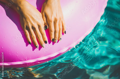woman manicured hands laying on the rubber ring in the swimming pool. Summer Vacation. Enjoying suntan. Weekend on resort
