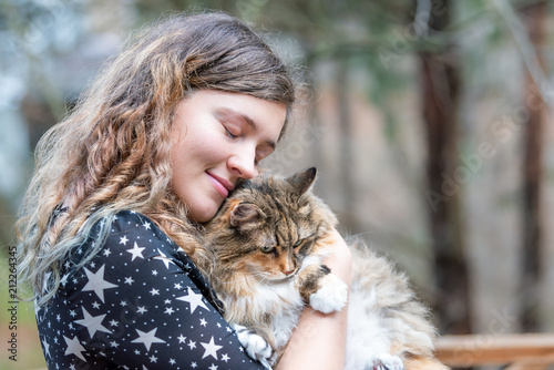фотографія Happy young woman in dress holding maine coon cat outside, outdoors during summe