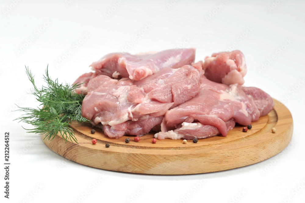 The fillet of the turkey hip is raw on a round wooden tray. Next to the meat is a branch of dill. White background. Close-up. The fillet of the turkey hip is raw on a round wooden tray. Next to the meat is a branch of dill. White background. Close-up.