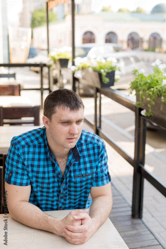 young man. the man in the shirt in the cage. portrait of a man. a man at a table in a cafe in the open area. young man. the man in the shirt in the cage. portrait of a man. a man at a table in a cafe in the open area.