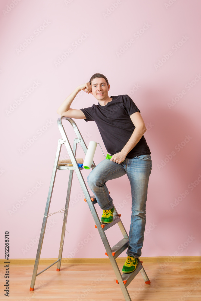 Photo of man with paint roller next to ladder