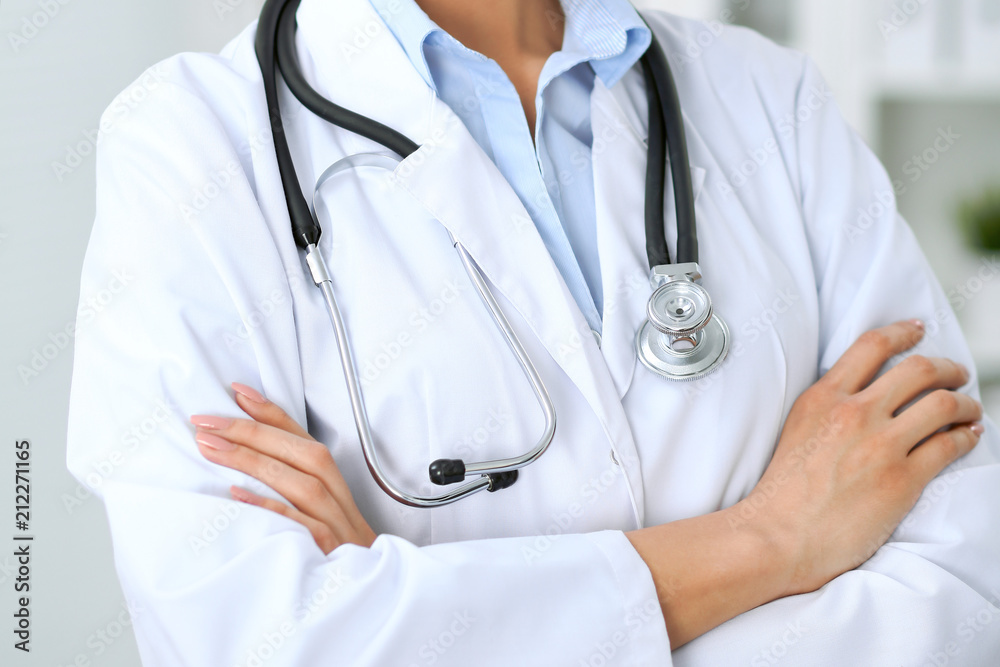 Closeup of doctor woman standing with arms crossed at hospital. Health care, insurance and help concept Closeup of doctor woman standing with arms crossed at hospital. Health care, insurance and help concept