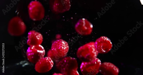 Raspberries falling into a water. black background photo