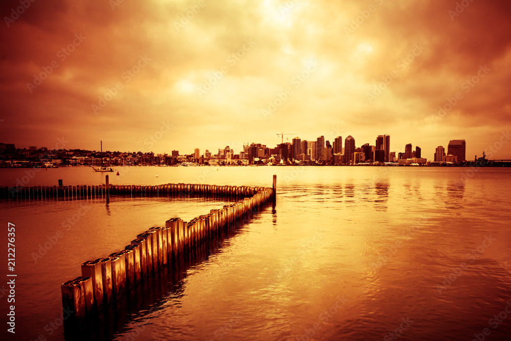 Beautiful sunset over San Diego skyline with bay and and line of wooden posts