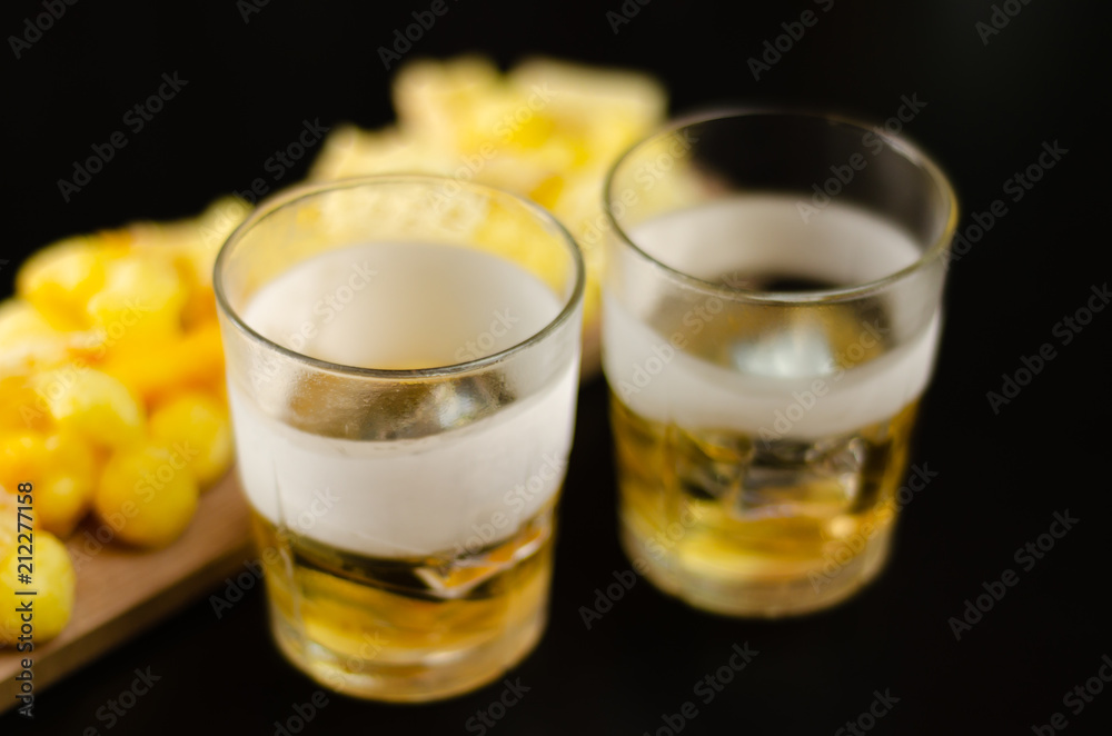 glass of whiskey with ice cubes and salty snacks on a black background glass of whiskey with ice cubes and salty snacks on a black background