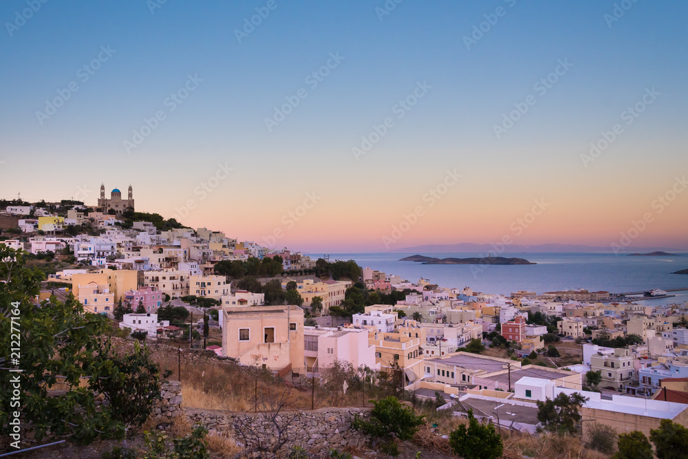 Panoramic view of Ermoupoli city of Syros Island in Cyclades, Greece. View of the houses, the port and the Orthodox Anastaseos church on sunset 