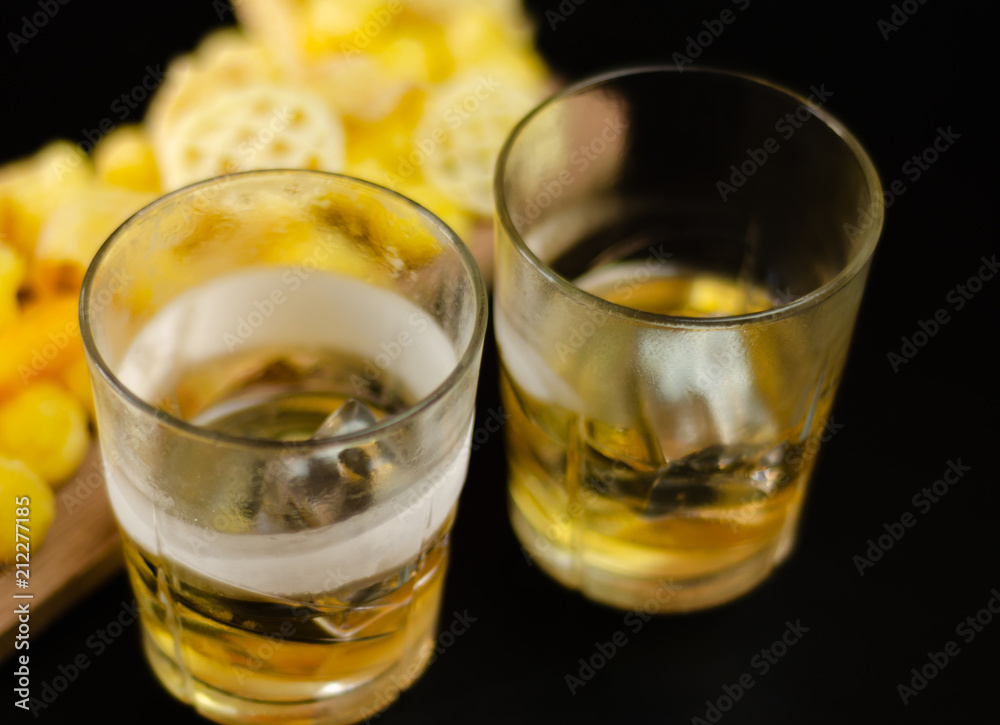 glass of whiskey with ice cubes and salty snacks on a black background glass of whiskey with ice cubes and salty snacks on a black background