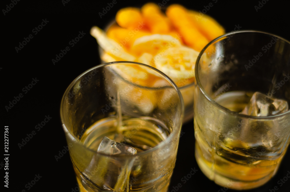 glass of whiskey with ice cubes and salty snacks on a black background glass of whiskey with ice cubes and salty snacks on a black background