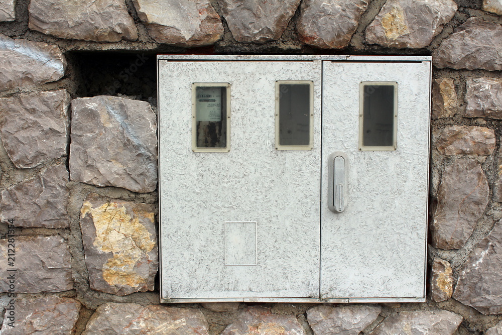 Electric meter box mounted on stone wall with one out of three meters inside and working Electric meter box mounted on stone wall with one out of three meters inside and working