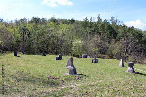 Glagolitic letters made from stone called Uspon Istarskog razvoda scattered over large grass area and surrounded with trees photo