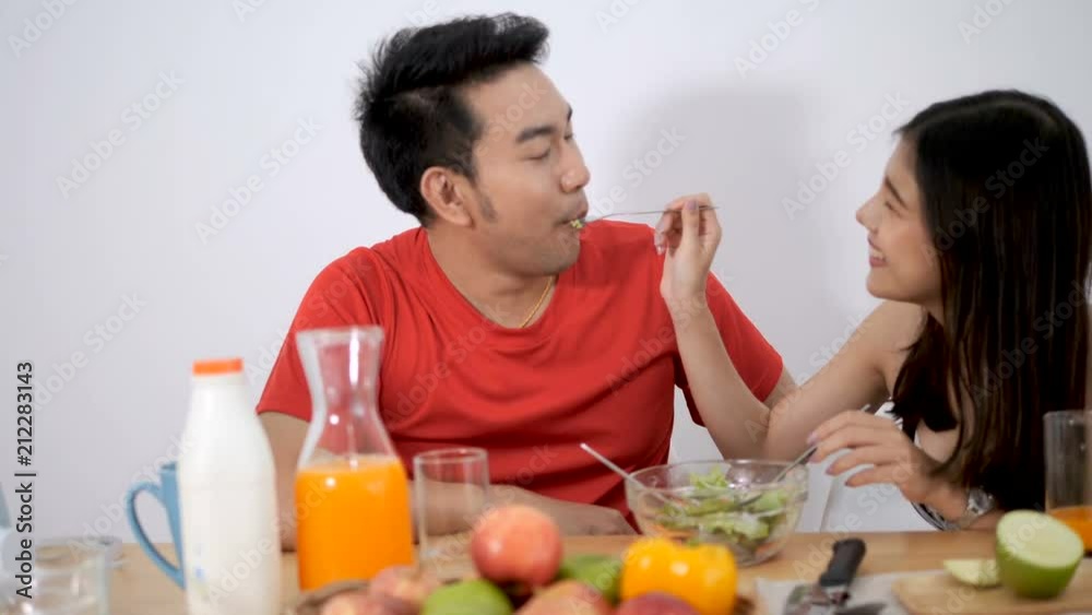 Asian couple feeding food to each other at home. Asian couple feeding food to each other at home.