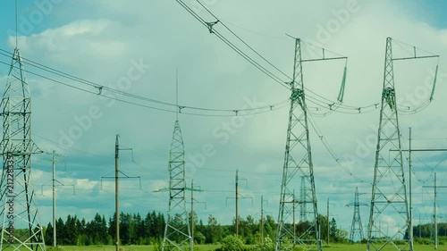 Several power line supports are in the background of moving clouds. The camera moves from the supports to the overall plan photo