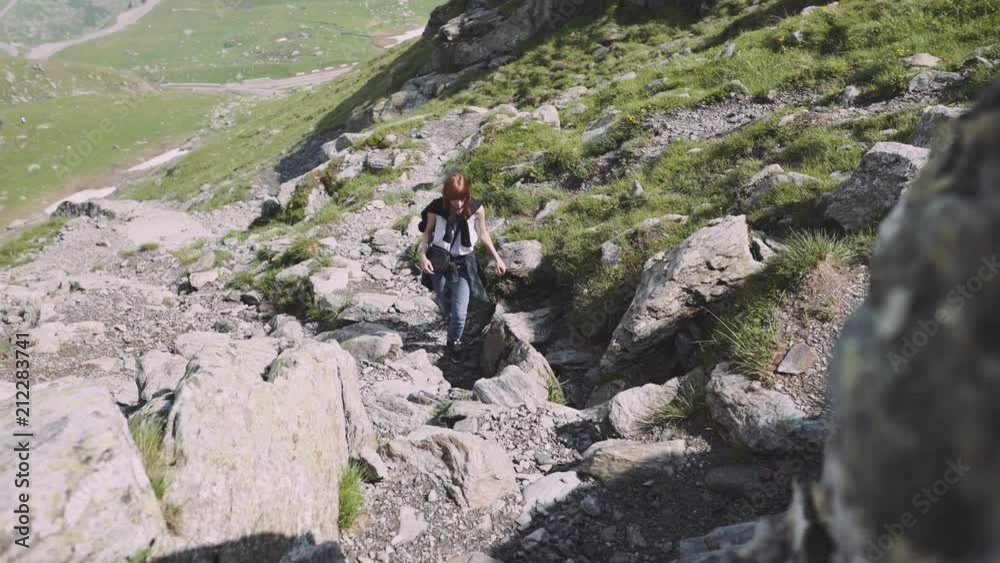 A young woman hiker climbs mountains with photo camera. Transfagarasan, Carpathian mountains in Romania A young woman hiker climbs mountains with photo camera. Transfagarasan, Carpathian mountains in Romania