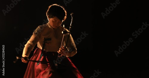 Korean female musician playing the Haegeum which is the Korean traditional string instrument on stage with spotlight