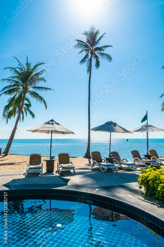 Beautiful tropical beach and sea with umbrella and chair around swimming pool