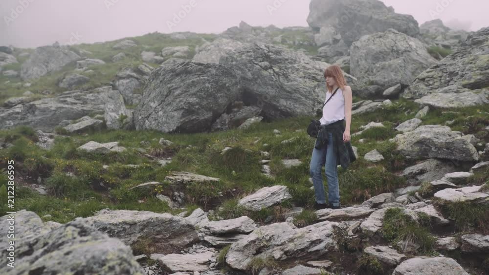 A young woman hiker climbs mountains with photo camera. Transfagarasan, Carpathian mountains in Romania A young woman hiker climbs mountains with photo camera. Transfagarasan, Carpathian mountains in Romania