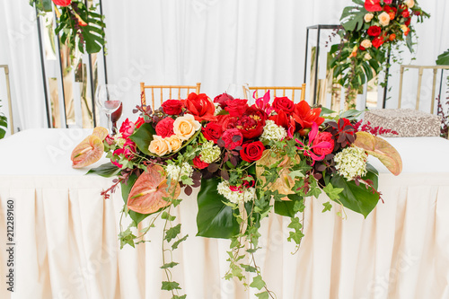 Beautiful banquet hall under a tent for a wedding reception. Interior of a wedding tent decoration ready for guests. Decor flowers. Red theme