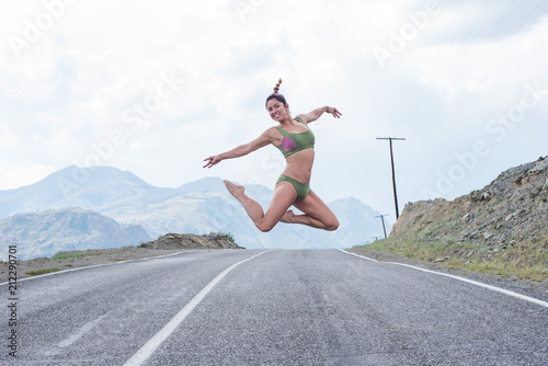 girl with red hair walking on a mountain road alone. woman walking alone on empty mountain road. woman jumping on empty mountain road