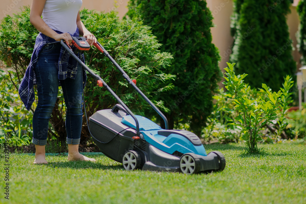 Gardener girl is cutting the grass with the mower Gardener girl is cutting the grass with the mower