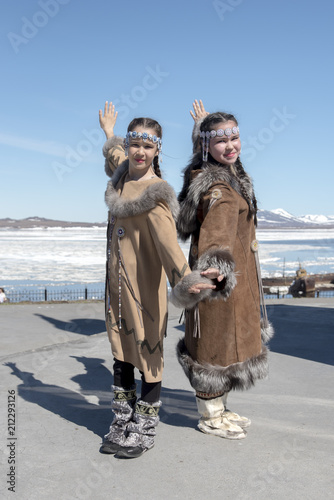 Two chukchi girls in folk dress show figure of traditional dance against the Arctic landscape