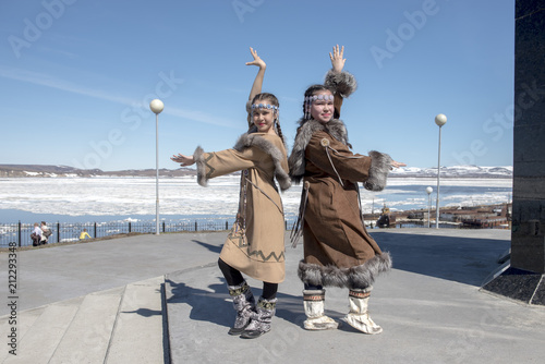 Two chukchi girl in folk dress against the Arctic landscape