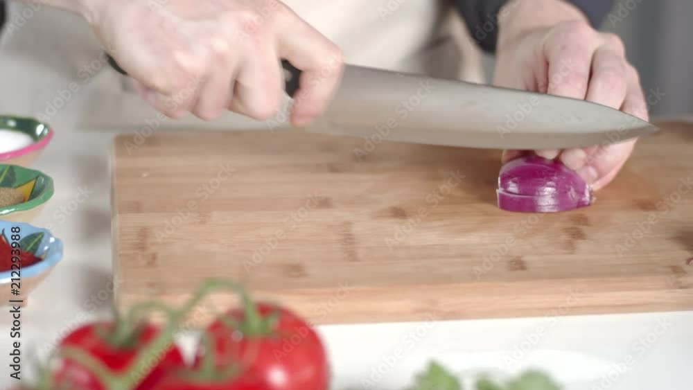 Slow-mo tracking shot of chef slicing red onion with large kitchen knife Slow-mo tracking shot of chef slicing red onion with large kitchen knife
